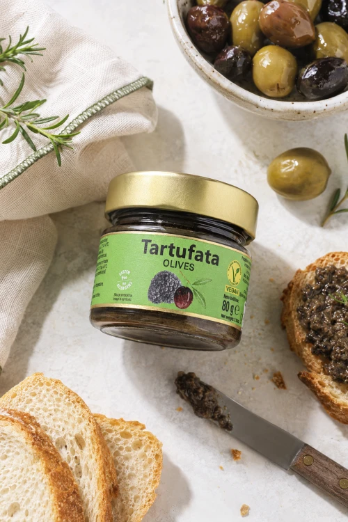 Zigante Tartufata Olives w aranżacji z czarnymi oliwkami, serem i jasną serwetką